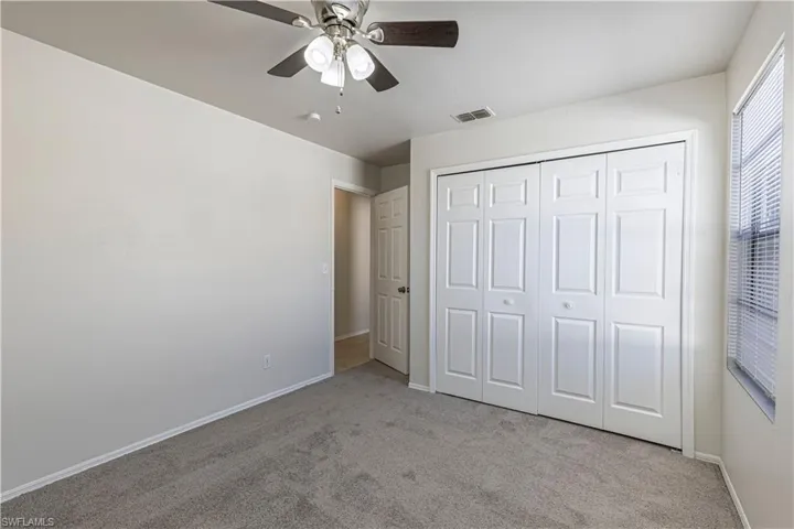 Unfurnished bedroom featuring light colored carpet, ceiling fan, and a closet