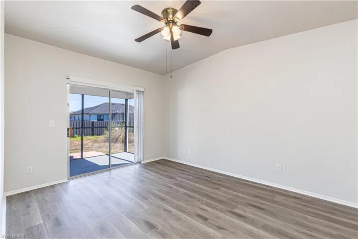 Unfurnished room featuring ceiling fan, wood finished floors, and lofted ceiling