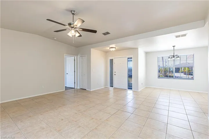 Spare room with a ceiling fan, hanging lights, light tile patterned flooring, and lofted ceiling