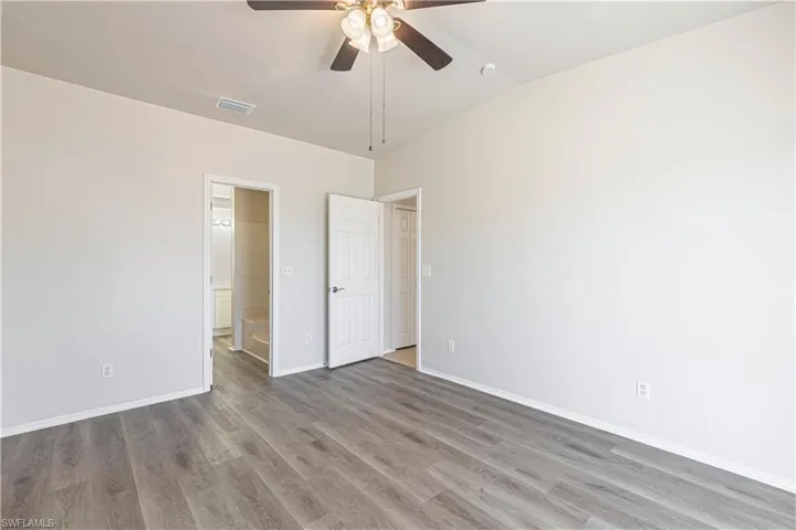 Unfurnished bedroom featuring a ceiling fan, wood finished floors, and connected bathroom