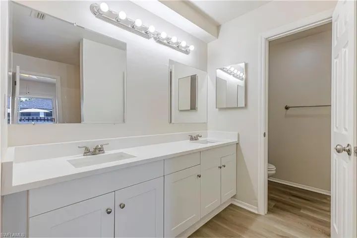Bathroom with double vanity and light wood-type flooring