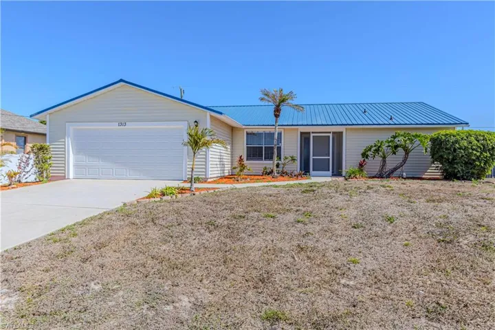 Single story home featuring an attached garage, a metal roof, and concrete driveway