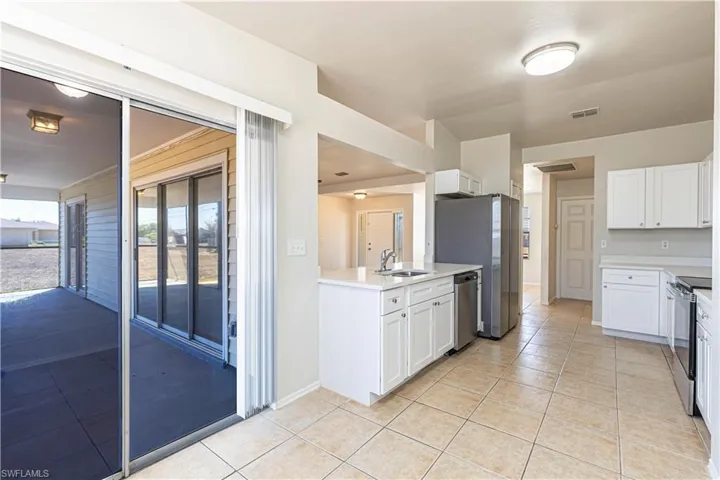 Kitchen featuring white cabinets, stainless steel appliances, light tile patterned flooring, a peninsula, and open floor plan