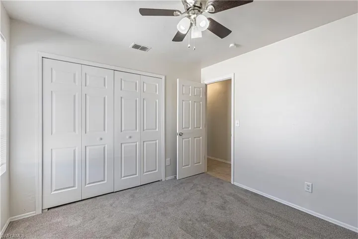 Unfurnished bedroom featuring carpet flooring, a ceiling fan, and a closet