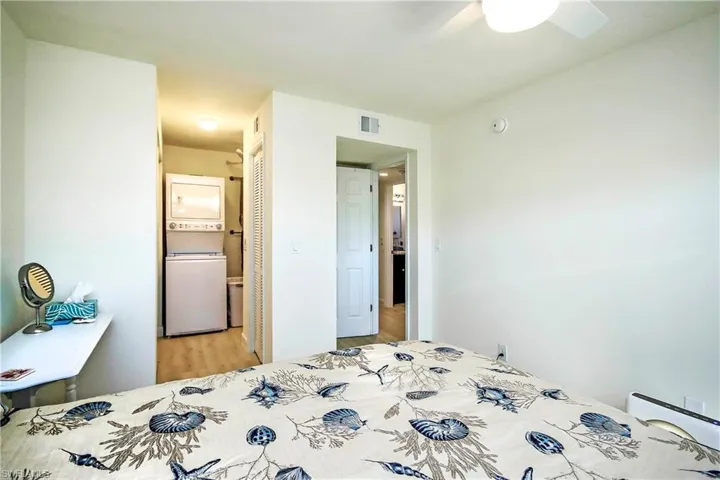 Bedroom featuring ceiling fan, light wood-style flooring, a closet, visible vents, and stacked washer / drying machine