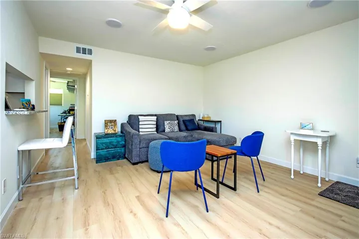 Living room featuring light wood finished floors, visible vents, baseboards, and a ceiling fan