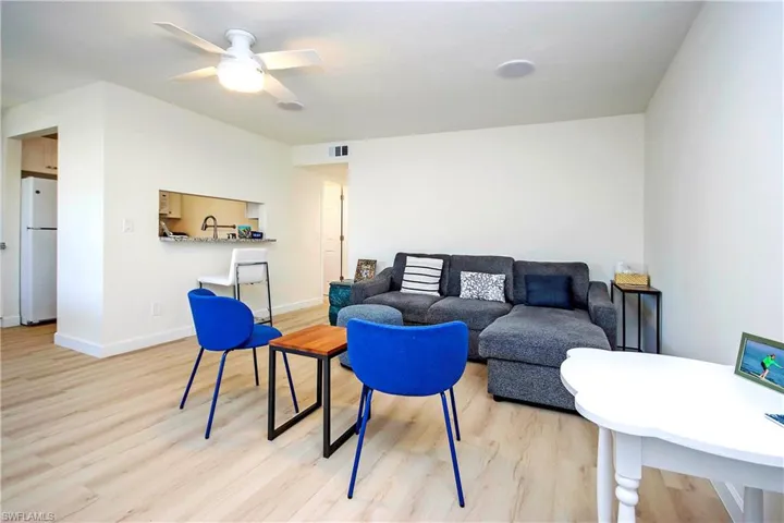 Living area with light wood-style floors, baseboards, visible vents, and a ceiling fan