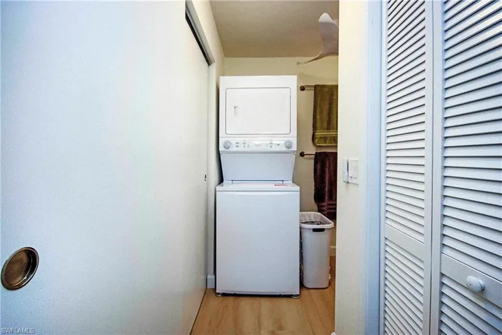 Laundry area featuring laundry area, stacked washer and clothes dryer, and wood finished floors