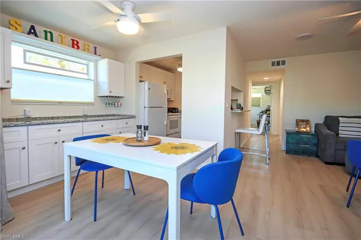 Kitchen with light wood-type flooring, freestanding refrigerator, a ceiling fan, visible vents, and stove
