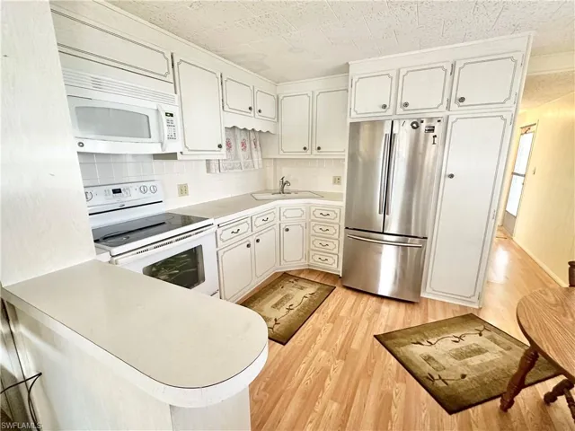 Kitchen with decorative backsplash, light hardwood / wood-style flooring, and white appliances