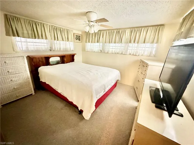 Bedroom with carpet flooring, a textured ceiling, and ceiling fan