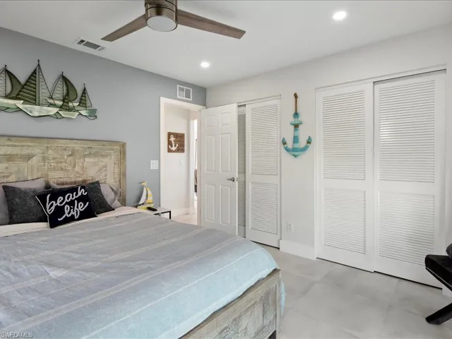 Tiled bedroom featuring multiple closets and ceiling fan