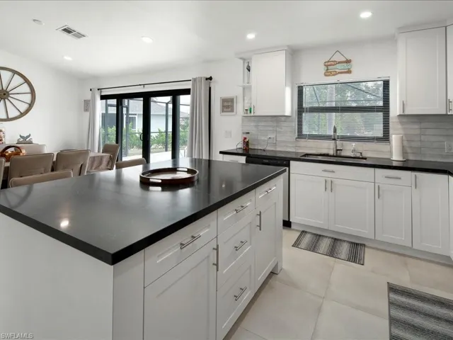 Kitchen featuring white cabinets, backsplash, sink, and light tile patterned floors