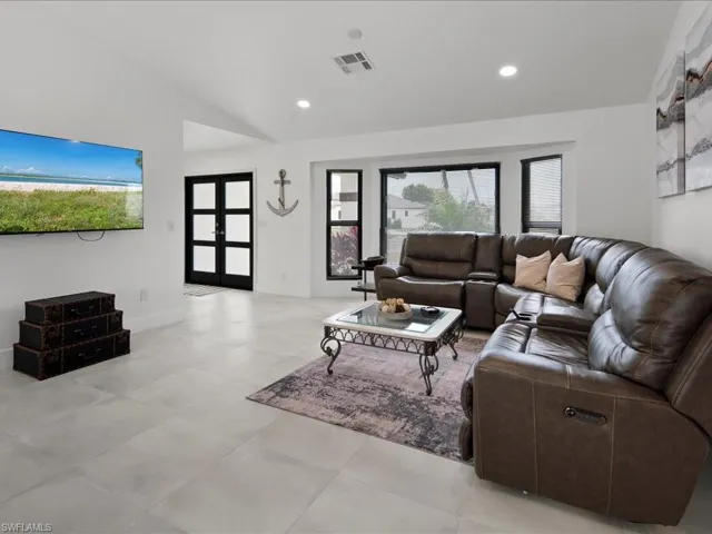Living room featuring light tile patterned flooring, a wealth of natural light, and lofted ceiling