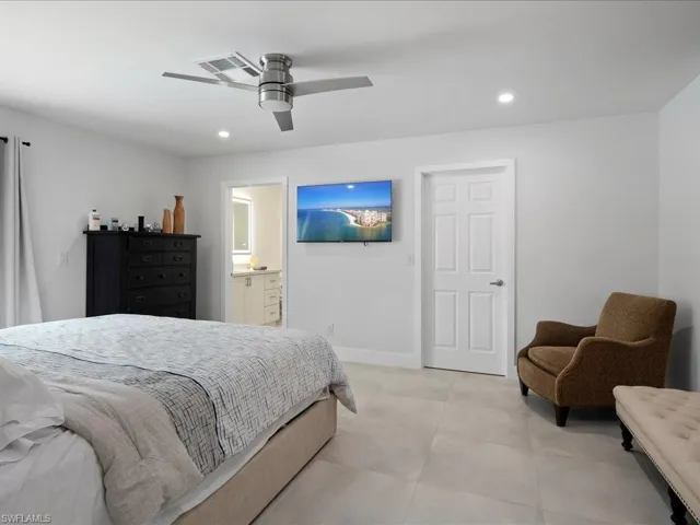 Tiled bedroom featuring ceiling fan and connected bathroom