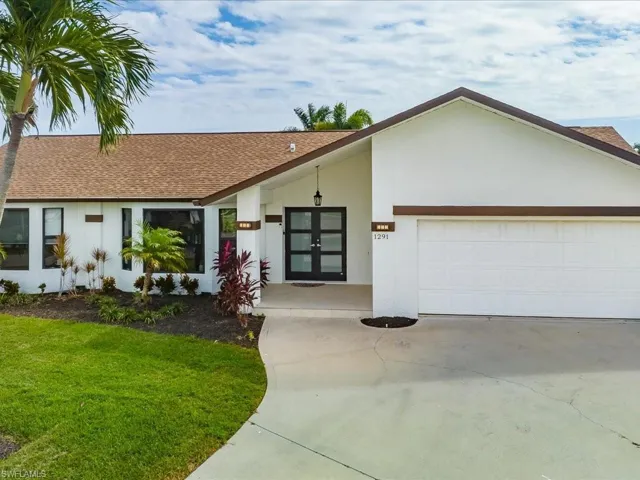 Ranch-style house featuring a garage, french doors, and a front lawn