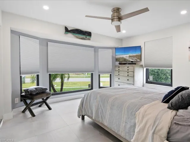 Bedroom featuring light tile patterned flooring, multiple windows, and ceiling fan