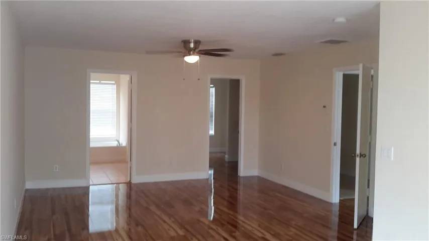 Empty room with dark wood-style floors and a ceiling fan