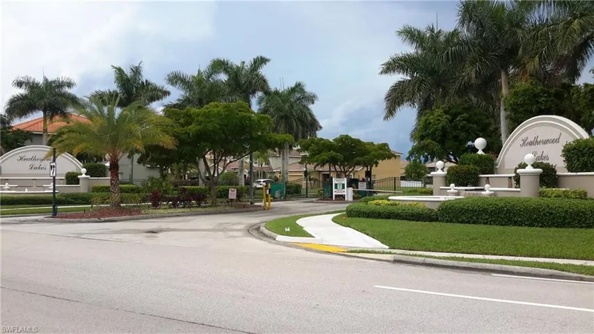 View of asphalt road featuring sidewalks, curbs, and a gated entry