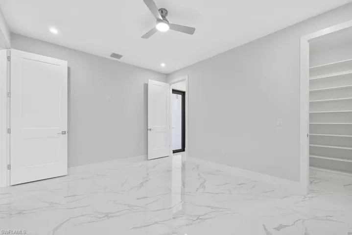 Unfurnished bedroom featuring a spacious closet, a closet, and ceiling fan