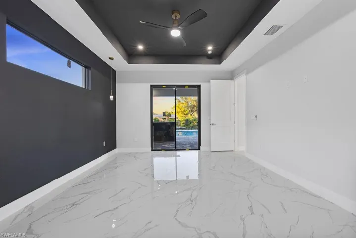 Empty room with ceiling fan and a tray ceiling