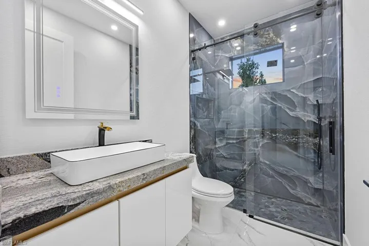 Bathroom with vanity, toilet, and a shower with door