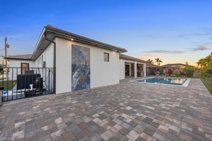 Pool at dusk featuring cooling unit and a patio area