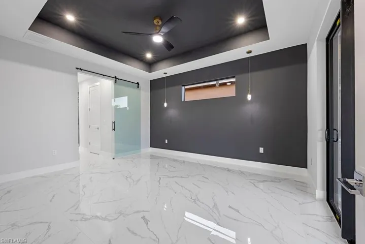 Spare room featuring a barn door, ceiling fan, and a tray ceiling