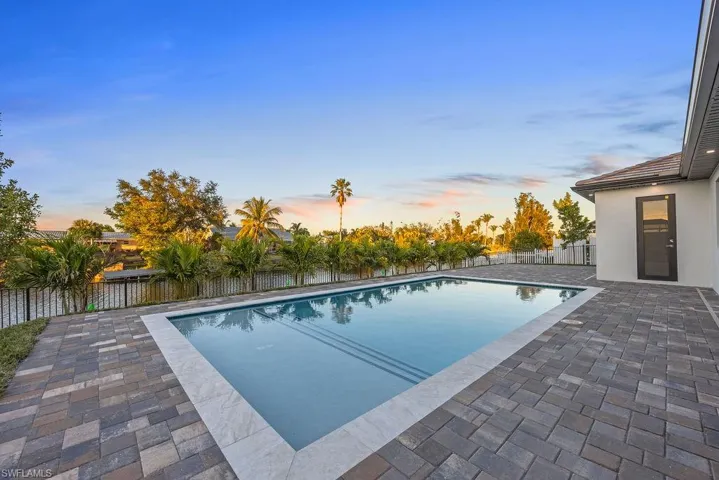 Pool at dusk featuring a patio area
