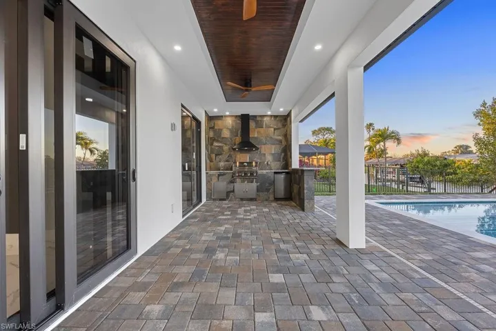 Patio terrace at dusk featuring a fenced in pool, area for grilling, and exterior kitchen