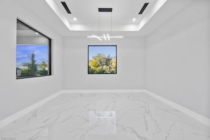 Empty room with an inviting chandelier and a tray ceiling