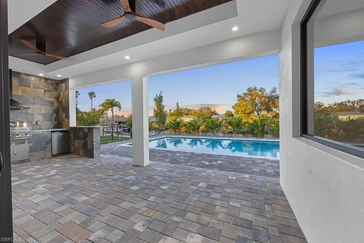 Pool at dusk with area for grilling and ceiling fan