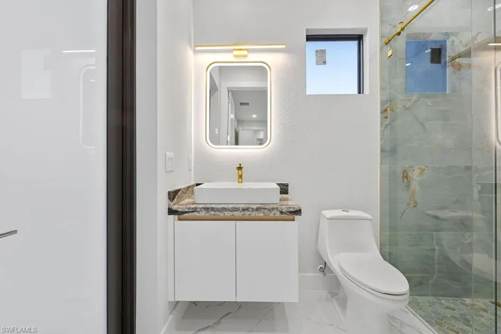 Bathroom featuring walk in shower, vanity, and toilet