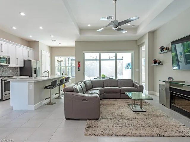 Living area featuring a chandelier, light tile patterned flooring, a tray ceiling, recessed lighting, and a ceiling fan
