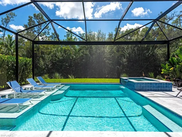 View of swimming pool featuring a pool with connected hot tub, glass enclosure, a sunroom, and a patio