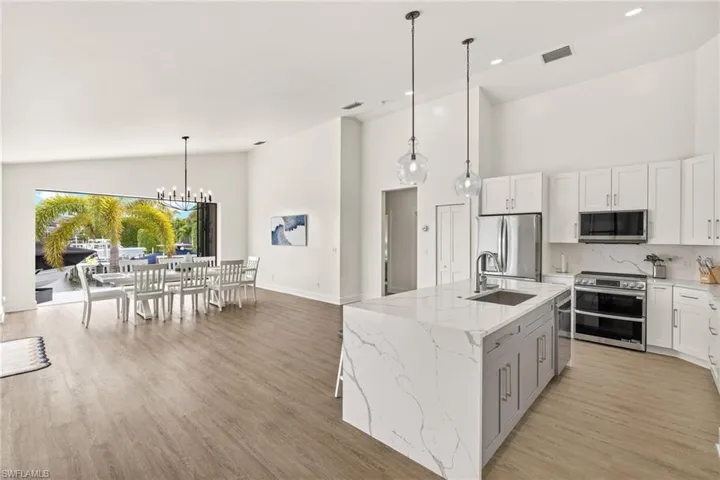 Kitchen featuring white cabinetry, an island with sink, and appliances with stainless steel finishes