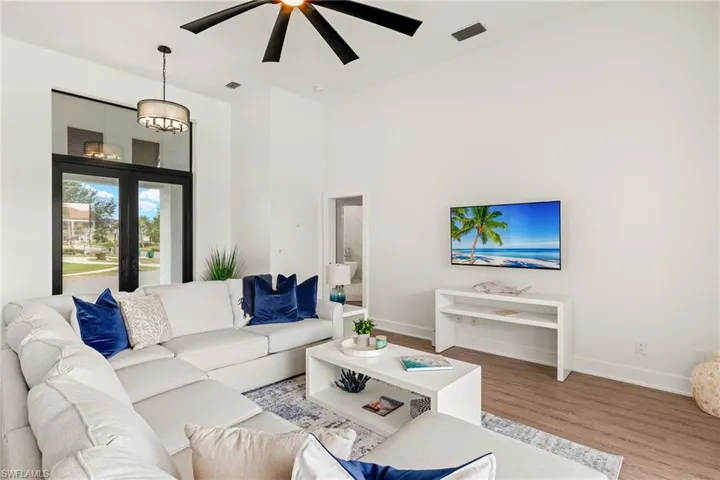Living room with wood-type flooring and ceiling fan with notable chandelier