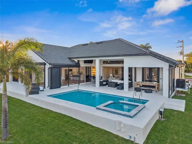 Rear view of property with a pool with hot tub, an outdoor hangout area, a patio, and a lawn