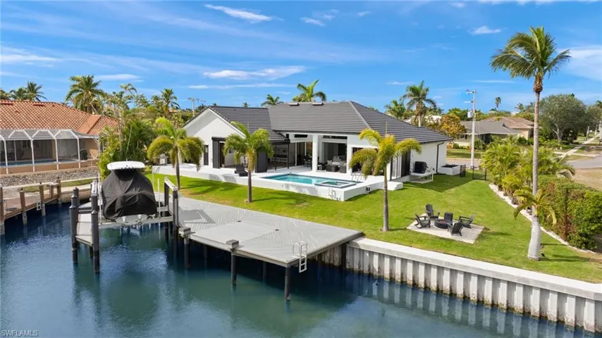 Back of property with a water view, a yard, a patio area, and a fire pit