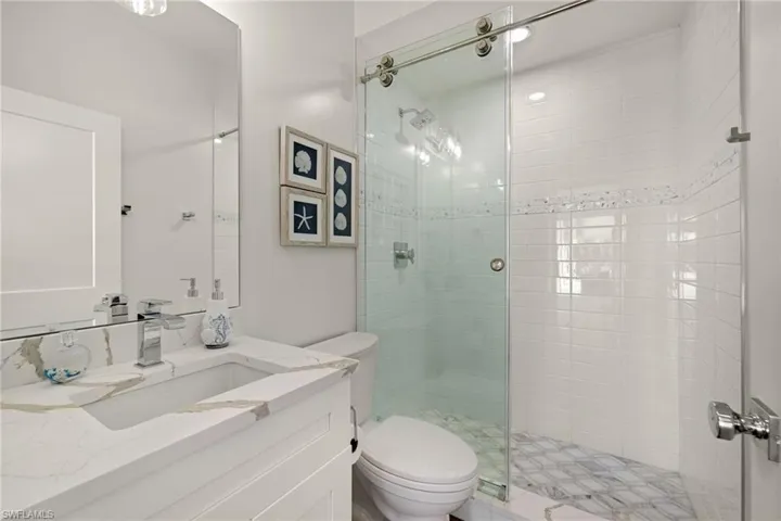 Bathroom with vanity, a shower with door, and toilet