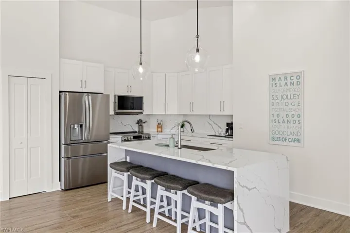 Kitchen featuring white cabinetry, appliances with stainless steel finishes, sink, and a center island with sink