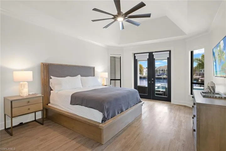 Bedroom featuring french doors, access to outside, a raised ceiling, ceiling fan, and light hardwood / wood-style floors