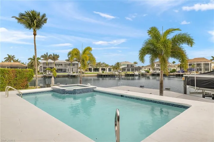 View of pool with an in ground hot tub, a water view, and a boat dock