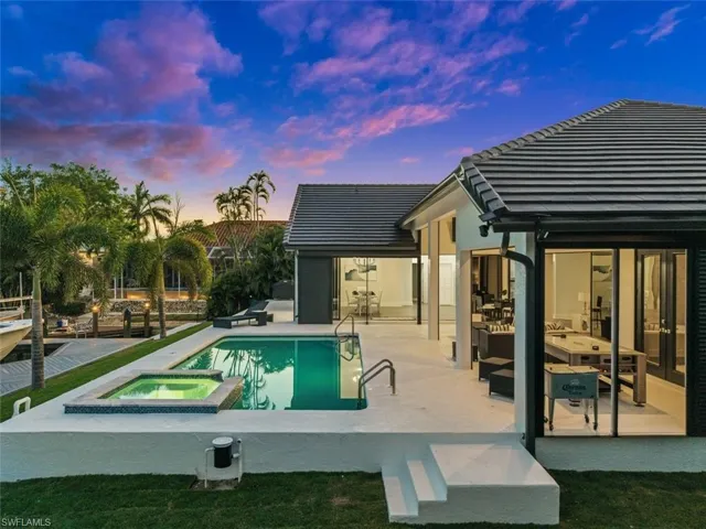Pool at dusk featuring a patio and an in ground hot tub