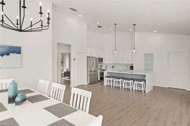 Dining room featuring sink, high vaulted ceiling, and light hardwood / wood-style flooring
