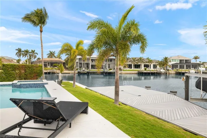 View of pool with a water view, an in ground hot tub, a lawn, and a boat dock