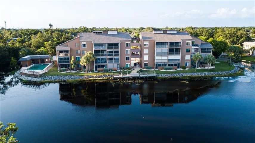 Rear view of house with a balcony, a swimming pool, and a water view