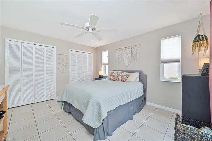 Bedroom featuring multiple closets, light tile patterned flooring, and a ceiling fan
