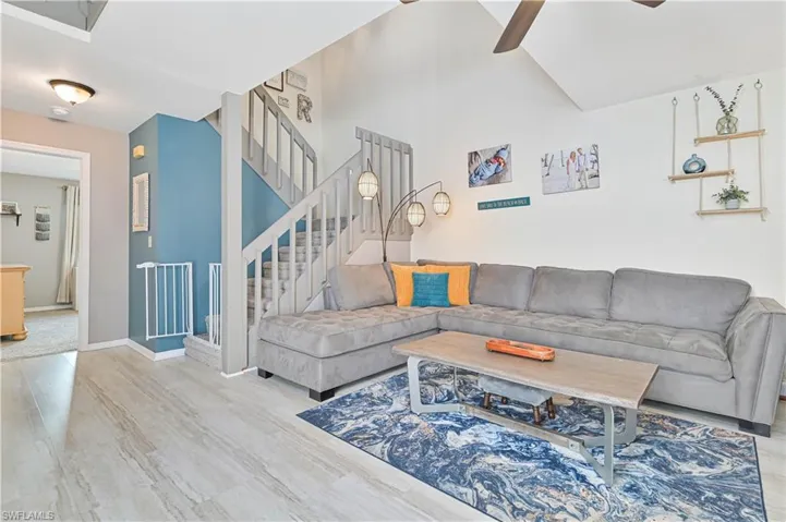 Living room featuring a ceiling fan, vaulted ceiling, and light wood finished floors