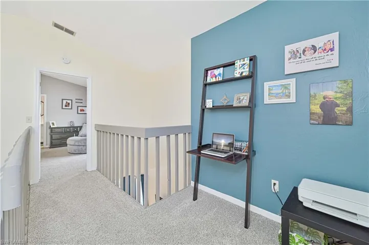 Hallway featuring light carpet and vaulted ceiling